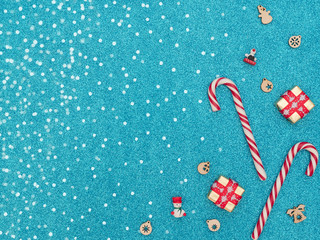 Two Christmas canes with two gift boxes and wooden Xmas decorations on blue background with white snow. New Year greeting card. Christmas, New Year concept. Flat lay style with copy space.