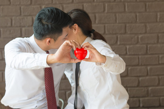 Businesspeople couple holding a red heart to a customer.