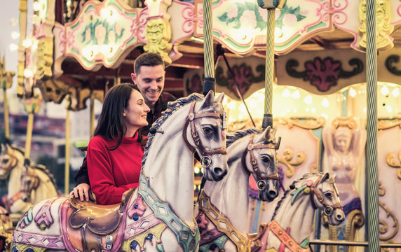 romantic couple taking a moment to kiss while riding horses on carousel