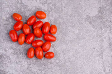 Fresh red cerry tomatoes on a grey structured background