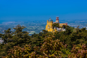 Fototapeta na wymiar The Pena Palace seen from the Gardens of Pena Park at the municipality of Sintra