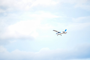 Light plane flying over a little cloudy blue sky