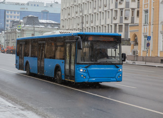 Fototapeta na wymiar bus moves in winter in snowfall on a city