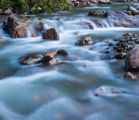 Wild nature concept. Raging mountain river running fast between small rocks and stones.