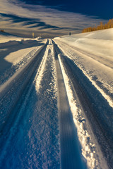 FEBRUARY 24, 2019 - RIDGWAY COLORADO USA - Winter snowy road through deep snow leads to San Juan Mountains leaving tire tread trails