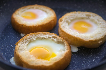 three eggs baked in round buns in a dark pan top view close-up