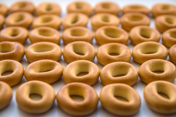 Many bagels stacked on a white kitchen table close-up