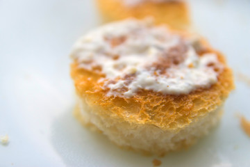 two round croutons with white sauce on top on a white background close up