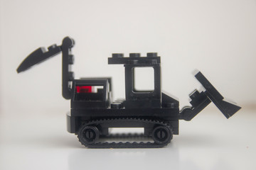 black toy bulldozer from designer cubes on white background close up