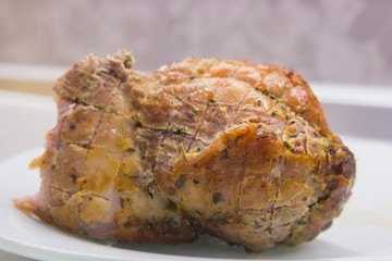 A piece of fried meat on a white plate close-up on a gray kitchen table