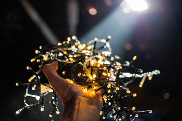 hand holding christmas lights on dark background