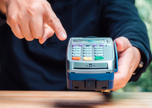 Male's hand with payment credit card through terminal for shopping retail. Payment terminal and credit card concept.