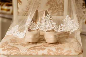 Bridal high heel shoes for happy wedding under veil on the chair