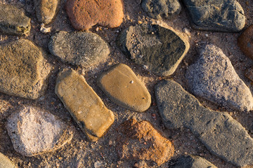 Background of colored stones. The surface is decorated with natural material. Pattern on the floor of multicolored pebbles.