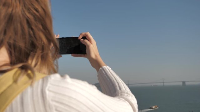 Young millennial woman tourist on holidays taking photo smartphone San Francisco
