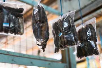 Dried sea cucumber tied into several bundles for sale, hanging from above, at a local fish market...