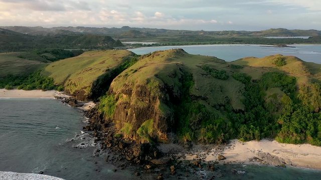Fantastic scenery of the green hills and white sandy beaches on the coast of Lombok. Merese Hills, Bali, Indonesia, Aerial dolly tilting down shot