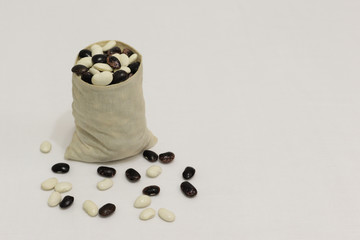 black and white beans in a linen bag on a white background