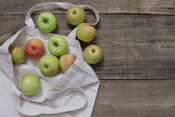 green apples in a linen bag on wooden table