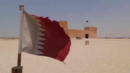 Slow pan of Qatar flag to reveal the Al Zubara Fort
