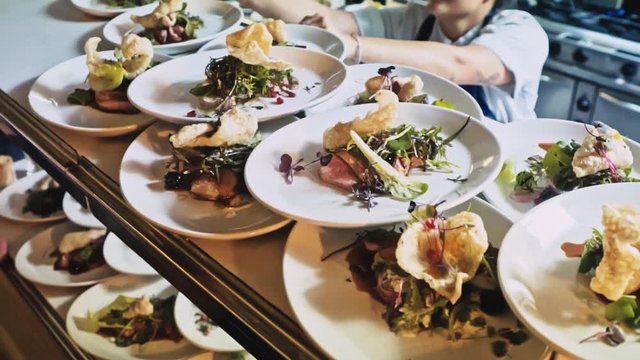 A stack of plates lines the counters of a restaurant kitchen, slow motion