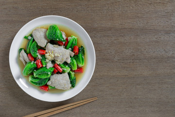 top view of stir fried cabbage sprout with pork in a ceramic dish on wooden table. homemade style food concept.