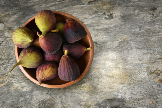 A Wood Bowl Filled With Fresh Ripe Calimyrna Figs On A Slate Table Top, With Copy Space.