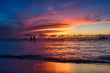 young couple strolls at low tide on a tropical island Holbox Mexico. Incredible sunset on the beach. Sky with incredible colors sun Caribbean sea