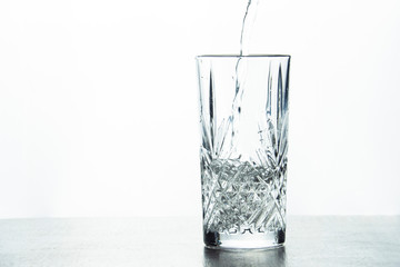 Water is poured into a crystal glass on a white background.
