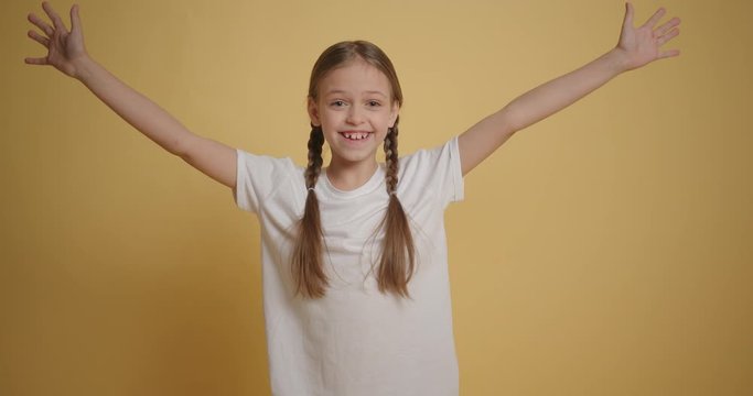 Girl full of joy jumps surprisingly into the frame at yellow wall slow motion
