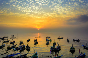 fishermen boats at sunrise on beach in surabaya, indonesia