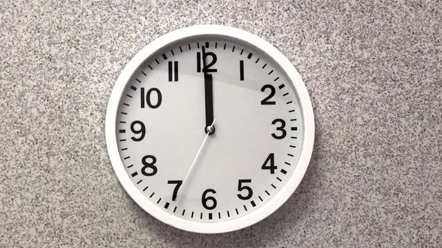 4K HD video white analog clock on grey textured wall ticking down seconds to midnight. New year non festive