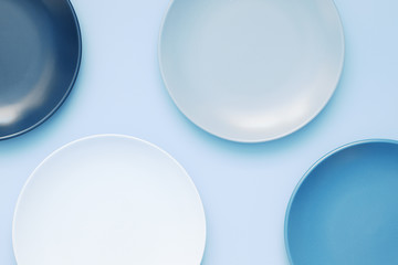 Blue empty ceramic plates on blue background. Trendy color dishware. Top view, flat lay, copy space