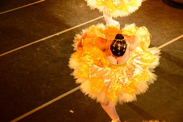 ballerina dancing in yellow dress, ballerina performing in bright yellow tutu seen from high angle, dancer in motion on stage floor, classical ballet performance concept, view from above © liligluck