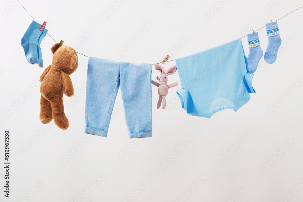 Wall mural baby clothes hanging on  rope on white background