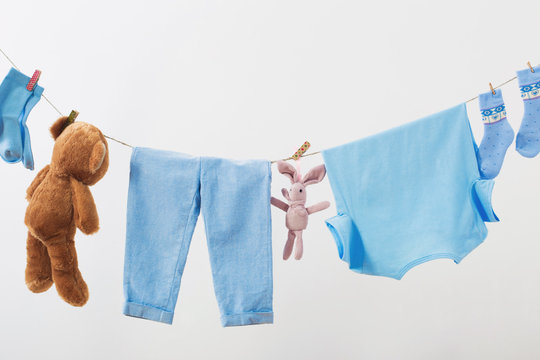 Baby Clothes Hanging On  Rope On White Background