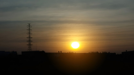 sunset in the city with silhouette of High voltage pole