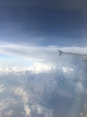 Fototapeta na wymiar an aerial view of mushroom shaped clouds from airplane cockpit window, vertical form