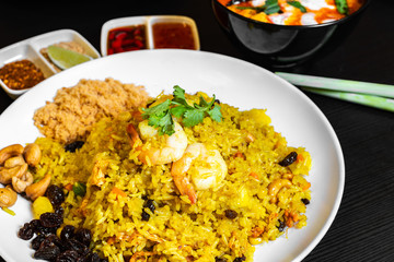 Pineapple Fried Rice and a bowl of Tom Yum Soup in the background. Typical famous Thailand cuisine food on table.