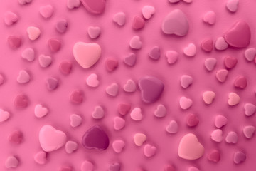 On a pink background there are a lot of small and large hearts. A gentle background with hearts. Toning is pink. Horizontal, close-up. Valentine's day.