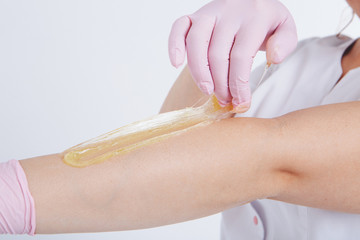 Hands in rubber gloves close-up. doctor puts wax, honey. medic is preparing for depilation. Concept of medicine, health care, beauty industry, hair removal, natural material. Copy space