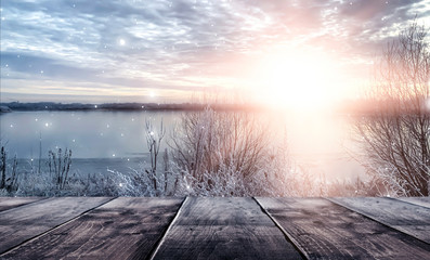 Winter background. Winter snow landscape with wooden table in front. Winter sun, ray, glare. Empty...