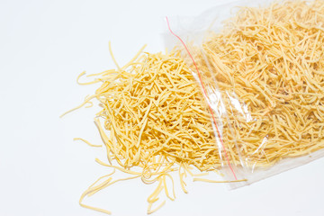 Homemade egg noodles in a plastic bag on a white background.