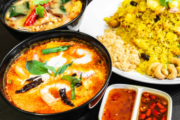 Tom Yum Soup or Tom Yam Kung is a traditional hot spicy sour soup, typical authentic dish in Thailand, usually cooked with shrimps. Pineapple fried rice in the background.