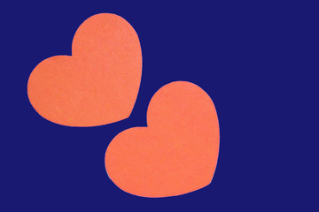 Two orange hearts isolated on a trendy bue background close-up. Top view, copy space. Valentine's Day greeting card