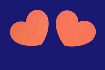 Two orange hearts isolated on a trendy bue background close-up. Top view, copy space. Valentine's Day greeting card