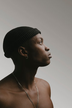 Profile of shirtless young man wearing knit cap and necklace