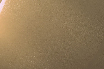 Sparkling drops of water on a metal surface illuminated by the sun close-up. Abstract background