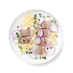 Salted herring with spices, lemon and red  onion rings isolated on white background. Marinated sliced fish. top view