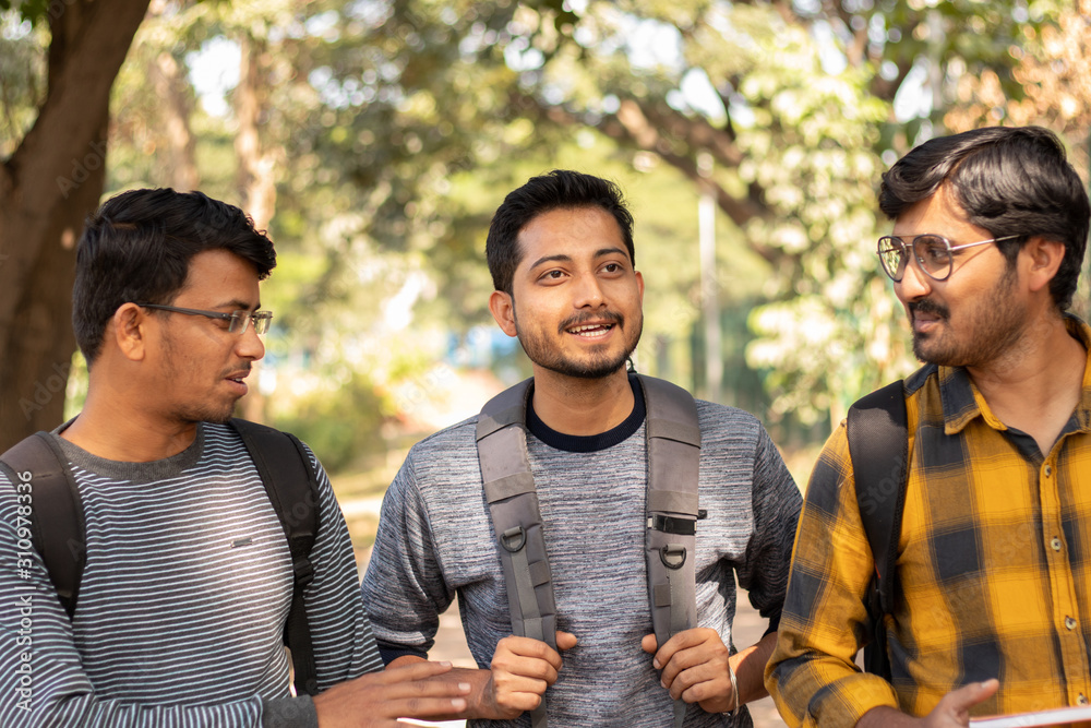 Wall mural three students talking or socializing at university campus - friends having fun and conversation at 